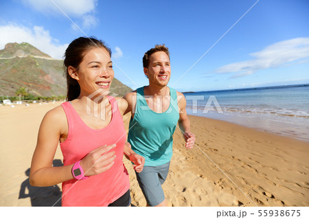 Running couple jogging on beach exercising Running couple jogging on beach exercising 55938675