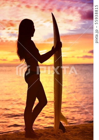 Surfer girl surfing looking at ocean beach sunset Surfer girl surfing looking at ocean beach sunset 55938815