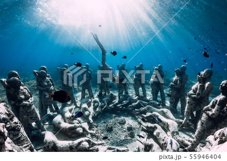 Woman freediver with fins dive near statues Woman freediver with fins dive near statues 55946404