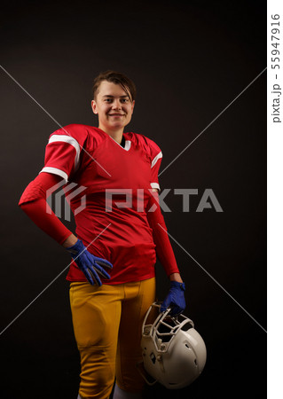 Picture of happy american brunette soccer player with helmet in her hand at empty black background 55947916