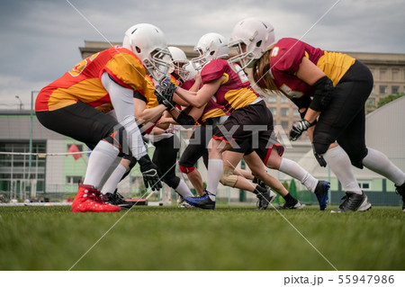 Photo of female team in helmets playing rugby on playground Photo of female team in helmets playing rugby on playground 55947986