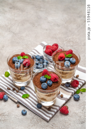 Classic tiramisu dessert with blueberries and raspberries in a glass on kitchen towel on concrete 55948116