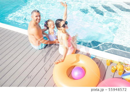 Parents and daughter feeling cheerful resting near pool Parents and daughter feeling cheerful resting near pool 55948572