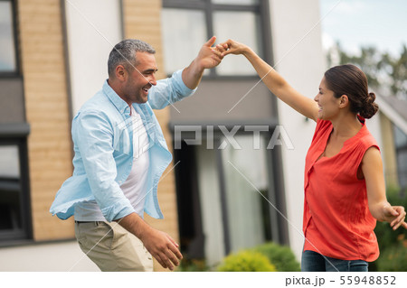 Grey-haired handsome husband dancing with wife outside Grey-haired handsome husband dancing with wife outside 55948852