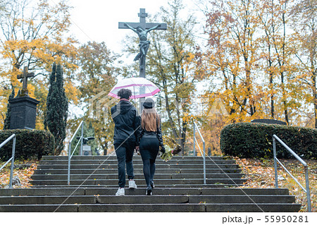 Man and woman walking up steps on cemetery towards a cross Man and woman walking up steps on cemetery towards a cross 55950281