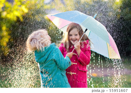 Kids with umbrella playing in autumn shower rain. 55951607