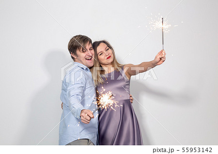 Celebration, fun and holiday concept - Happy man and woman hold a firework stick or sparklers 55953142