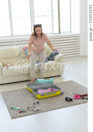 Vacation, travel and holidays concept - young woman collecting things for the trip 55953243