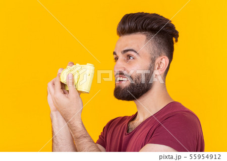 Portrait of a positive handsome young man with a beard holding a yellow vintage camera in his hands Portrait of a positive handsome young man with a beard holding a yellow vintage camera in his hands 55954912