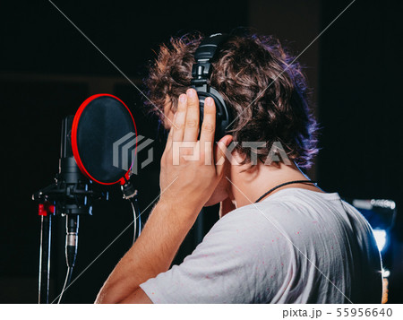 Young handsome singer man puts on headphones in the studio. 55956640