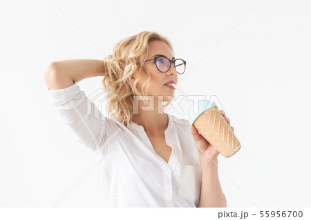 Beautiful positive young girl in a white shirt holds a cocktail in her hands posing for a white Beautiful positive young girl in a white shirt holds a cocktail in her hands posing for a white 55956700