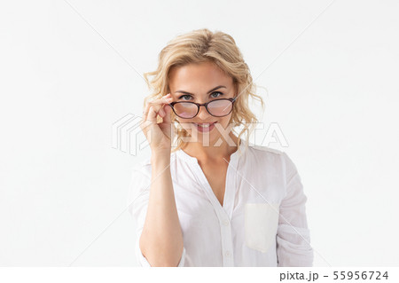 Vision, optics and beauty - Young blond woman putting on a pair of glasses on white background Vision, optics and beauty - Young blond woman putting on a pair of glasses on white background 55956724