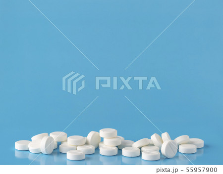 Heap of round white pills. Blue background with text space 55957900