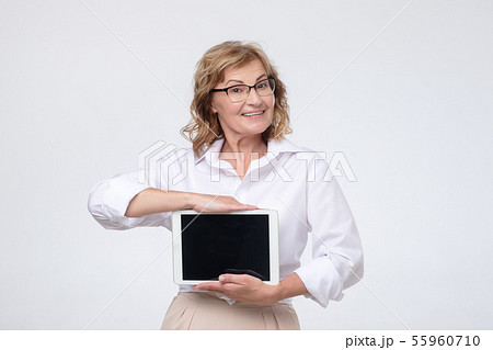 Mature caucasian woman shows a screen digital tablet. 55960710