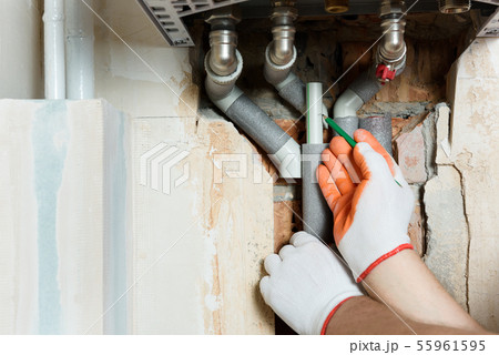 A worker is installing the gas boiler pipes. 55961595