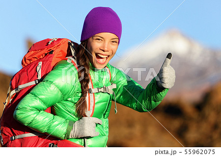 Hiking woman in winter jacket giving thumbs up 55962075