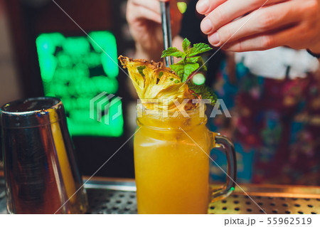 Bartender finished decorating his cocktail with mint and orange slice. 55962519