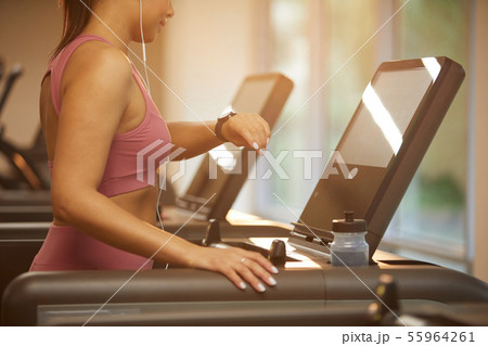 Woman Checking Watch while Running on Treadmill Woman Checking Watch while Running on Treadmill 55964261