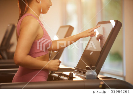 Woman Setting Up Treadmill in Gym Woman Setting Up Treadmill in Gym 55964262