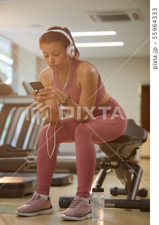 Beautiful Woman Using Smartphone in Gym Beautiful Woman Using Smartphone in Gym 55964333