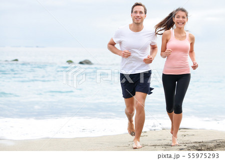 Exercising running couple jogging on beach 55975293