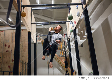 Powerful man with physical disability performing pull up exercise on one hand Powerful man with physical disability performing pull up exercise on one hand 55982623