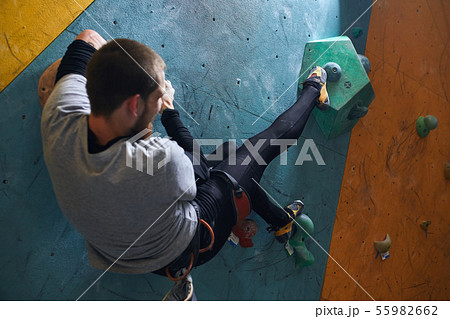 Rare view of powerful mountaineer climbing at artificial rock wall Rare view of powerful mountaineer climbing at artificial rock wall 55982662
