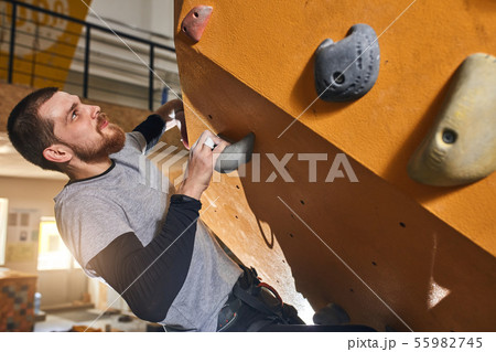 Cheerful rock-climber without forearm training at indoor bouldering gym Cheerful rock-climber without forearm training at indoor bouldering gym 55982745