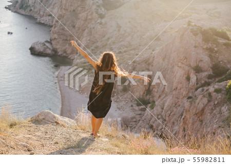 Woman with long curly hair on top of mountain. 55982811