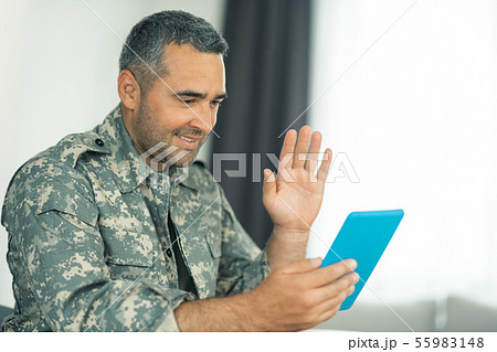 Military man waving while having video chat with family Military man waving while having video chat with family 55983148