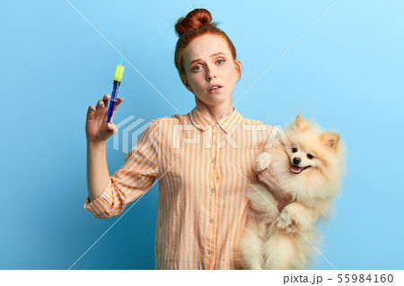 woman in striped shirt giving medicine to her pet wich has problems with health 55984160