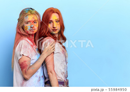 two sisters with dirty faces and closes standing over blue background 55984950