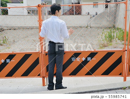 空き地前のフェンスに1人たたずむ男性 55985741