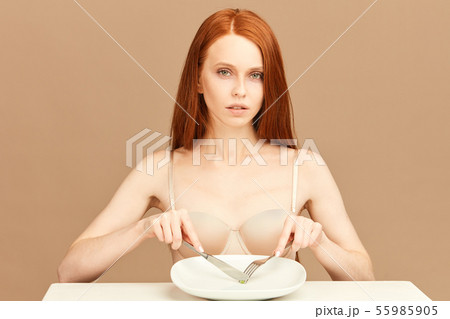 Red-haired woman eating one green pea with fork and knife. Diet Concept. Red-haired woman eating one green pea with fork and knife. Diet Concept. 55985905
