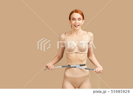 Happy top model in underwear celebrates diet results, measuring waist with tape Happy top model in underwear celebrates diet results, measuring waist with tape 55985929