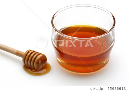 Honey dripping from dipper and honey in glass bowl 55986618