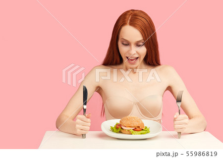 Red-haired skinny woman with greedy eyes being ready to eat burger. 55986819