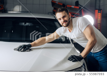 positive good looking mechanic cleaning the surface of his car 55987093