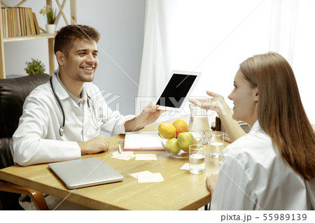 Smiling nutritionist showing a healthy diet plan to patient Smiling nutritionist showing a healthy diet plan to patient 55989139