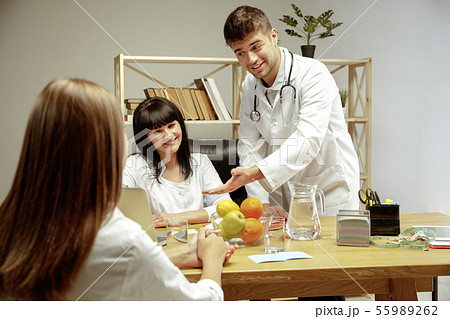 Smiling nutritionists showing a healthy diet plan to patient 55989262