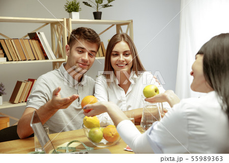 Smiling nutritionist showing a healthy diet plan to patient Smiling nutritionist showing a healthy diet plan to patient 55989363