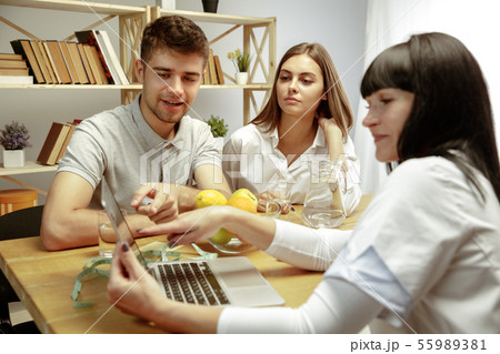 Smiling nutritionist showing a healthy diet plan to patient 55989381
