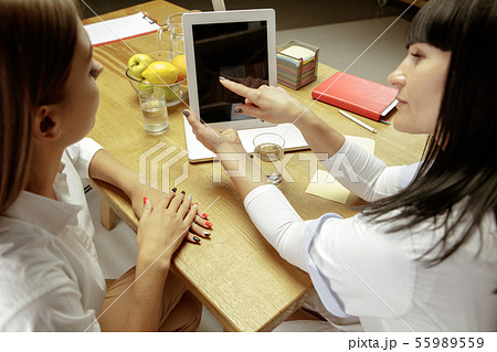 Smiling nutritionist showing a healthy diet plan to patient 55989559
