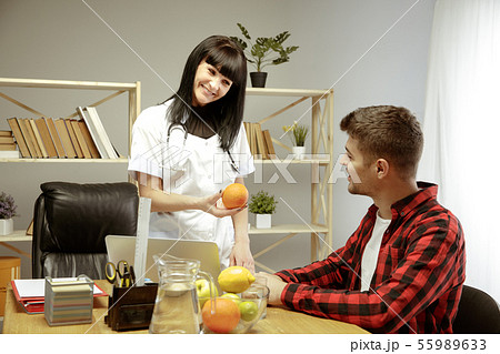 Smiling nutritionist showing a healthy diet plan to patient Smiling nutritionist showing a healthy diet plan to patient 55989633