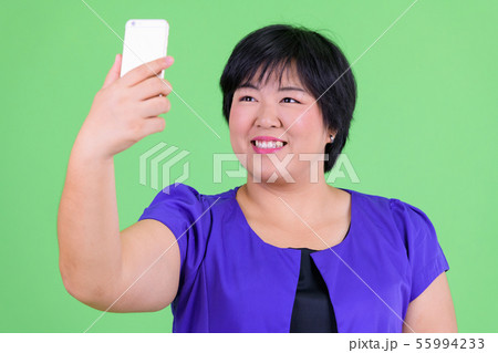 Young happy overweight Asian woman taking selfie 55994233