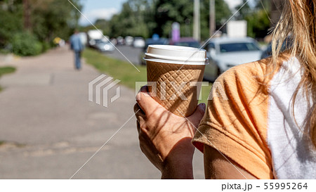 Holding takeaway coffee cup on the street Holding takeaway coffee cup on the street 55995264