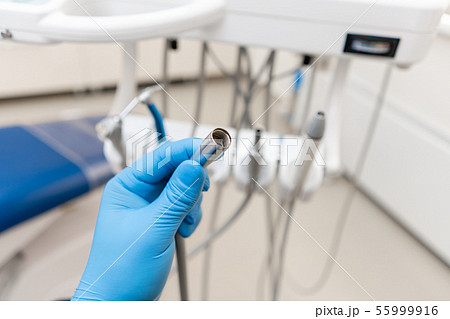 Close-up hand of dentist in the glove holds dental high speed turbine. Office where dentist conducts Close-up hand of dentist in the glove holds dental high speed turbine. Office where dentist conducts 55999916