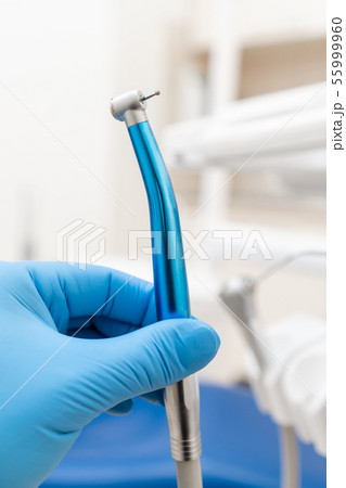 Close-up hand of dentist in the glove holds dental high speed turbine. Office where dentist conducts Close-up hand of dentist in the glove holds dental high speed turbine. Office where dentist conducts 55999960