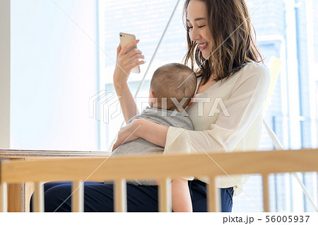 子供を抱きながらスマホを触る女性 56005937