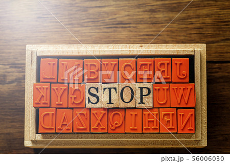 木目の上に置いたハンコ　STOP の文字と木目の背景 56006030
